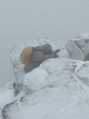 Mężczyzna wychodzi po zaśnieżonej półce skalnej