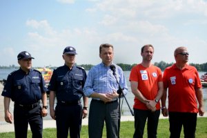 minister Mariusz Błaszczak przemawia stojąc w towarzystwie dwóch policjantów i dwóch ratowników wodnych