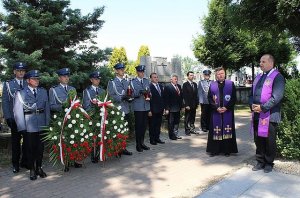 grupa siedmiu policjantów stoi trzymając dwa wieńce nagrobne, w towarzystwie dwóch księży i trzech zaproszonych gości