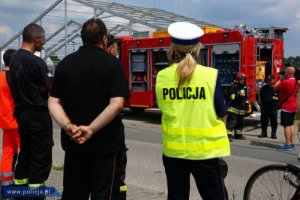 policjanci i strażacy stoją przy wozie strażackim