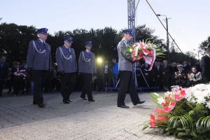 policjanci składają kwiaty przed pomnikiem upamiętniającym ofiary nalotów