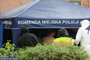 ludzie pod namiotem promocyjnym KMP we Wrocławiu w płaszczach przeciwdeszczowych
