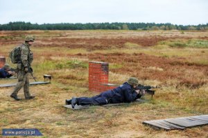 szkolenie na strzelnicy dwaj policjanci leżą i celują karabinami do celu, żołnierz kontroluje przebieg strzelań
