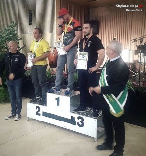 St. sierż. Konrad Adamaszek  stoi na najwyższym podium zawodów po bokach dwaj inni zawodnicy