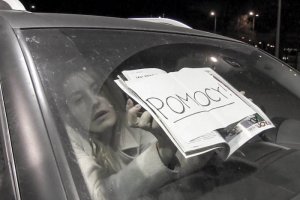 dziewczyna w samochodzie trzyma kartkę z napisem &quot;Pomocy!&quot;