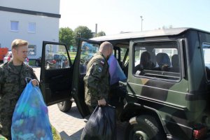 żołnierze wkładają worki z zebranymi zabawkami i przyborami szkolnymi do samochodu