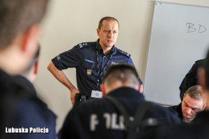 Policjant ruchu drogowego przemawia do siedzących na sali odpraw policjantów.