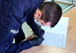 Na zdjęciu nowo przyjęty policjant podpisuje dokumenty.