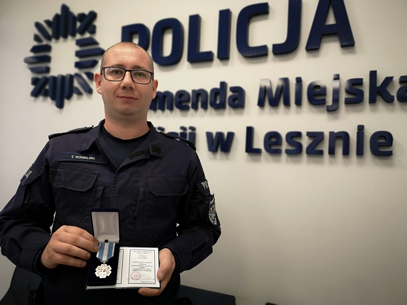 Sierżant sztabowy Tomasz Kowalski z Komendy Miejskiej Policji w Lesznie trzyma w ręku odznaczenie i legitymację