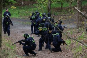 policjanci poruszają się drogą leśną, zabezpieczenie tyłów szyku