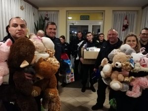 policjanci wraz z prezentami wchodzą do placówki pomocowej samotnym matkom i małym dzieciom