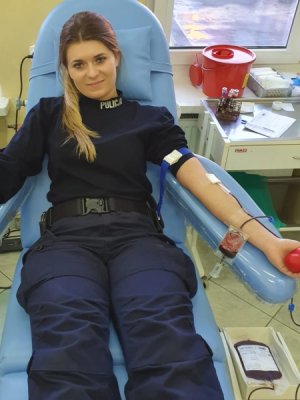 Młoda policjantka oddaj krew na fotelu w centrum krwiodawstwa.