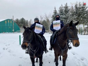 policjanci na koniach służbowych, w ręce trzymają kalendarz przeznaczony na aukcje