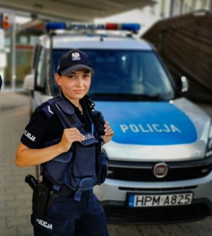 Umundurowana policjantka, która stoi przed radiowozem
