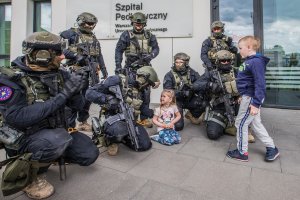 Policyjni kontrterroryści wraz z dziećmi przed wejściem do szpitala.