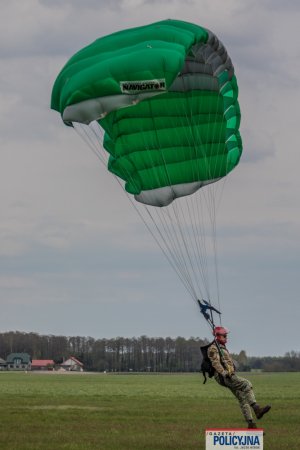 funkcjonariusz BOA ląduje ze spadochronem na lotnisku trawiastym
