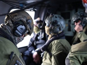 Wnętrze helikoptera z siedzącymi blisko siebie policyjnymi kontrterrorystami w kaskach, słuchawkach, specjalistycznych okularach oraz materiałowych maskach na twarzy.