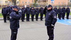 Komendant Główny Policji gen. Insp. Jarosław Szymczyk przyjmuje meldunek od stojącego przed nim oficera Policji, w tle widać stojących w dwuszeregu umundurowanych policjantów