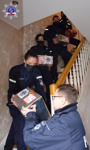 policjanci i policjantki stoją na schodach i podają sobie prezenty