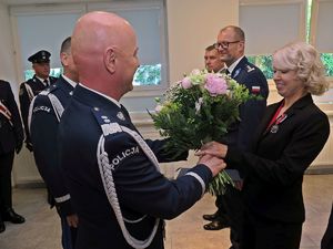 Komendant Główny Policji w mundurze wręcza kobiecie kwiaty
