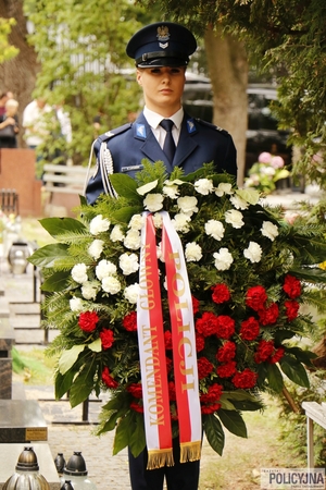 Policjantka trzyma wieniec kwiatów