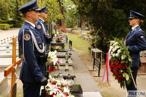 dwaj policjanci na warcie honorowej przy grobie generała Papały, naprzeciwko nich policjantka z wieńcem kwiatów