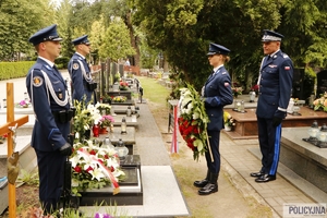 dwaj policjanci na warcie honorowej przy grobie generała Papały, naprzeciwko nich policjantka z wieńcem kwiatów, obok niej stoi nadinspektor Roman Kuster