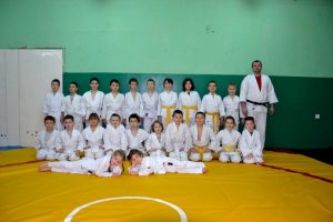 stojąca grupa dzieci i asp. sztab. Paweł Penszko w strojach do judo