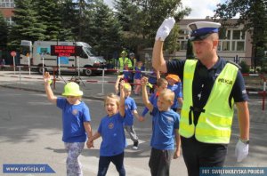 policjant przeprowadza grupę dzieci na drugą stronę ulicy