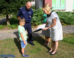 mały chłopiec przyjmuje gratulacje od kobiety i policjanta
