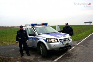 dwaj polscy policjanci przy radiowozie