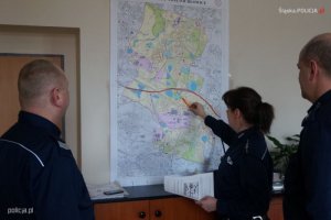 policjantka pokazuje punkty na mapie dwaj policjanci patrzą