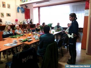kobiety siedzą przy stole policjantka stoi