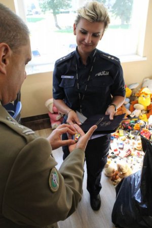 Ppłk Wojciech Luzak oraz policjantka i żołnierze z zebranymi zabawkami i przyborami szkolnymi
