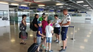 policjant rozmawia z turystami na lotnisku