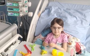 dziewczynka leży na łóżku szpitalnym, w ręku trzyma zabawkę