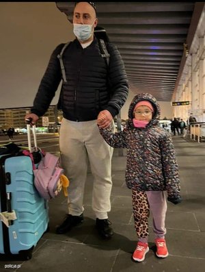 dziewczynka na lotnisku z tatą, tata trzyma niebieską walizkę