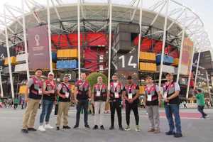grupa mężczyzn stoi przed stadionem w Katarze