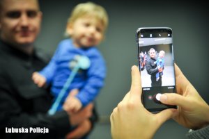Zdjęcie robione telefonem komórkowym policjanta z dzieckiem na ręku