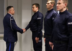 Umundurowani policjanci stojący w szeregu w sali