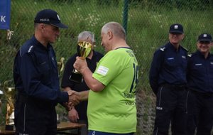 Fotografia kolorowa przedstawiająca Komendanta Komisariatu Policji w Pruchniku wręczającego puchar zawodnikowi z Nowego Targu.