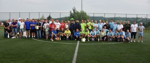 Fotografia kolorowa - grupowe zdjęcie wykonane na boisku wszystkich wszystkich uczestników  turnieju.