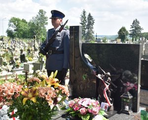 Fotografia kolorowa przedstawiająca nagrobek gen. Marka Papały, przy którym wartę honorową pełni umundurowany policjant.
