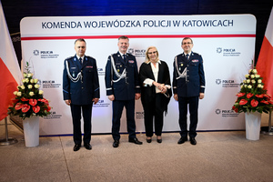 Zdjęcie przedstawia trzech policjantów oraz kobietę, osoby stoją przed napisem Komenda Wojewódzka Policji w Katowicach