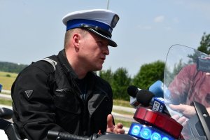 Policjant ruchu drogowego na motocyklu udziela wywiadu mediom.