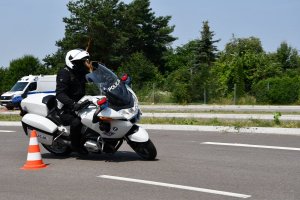Policjant na motocyklu BMW jedzie slalomem omijając pachołki ustawione na jezdni.
